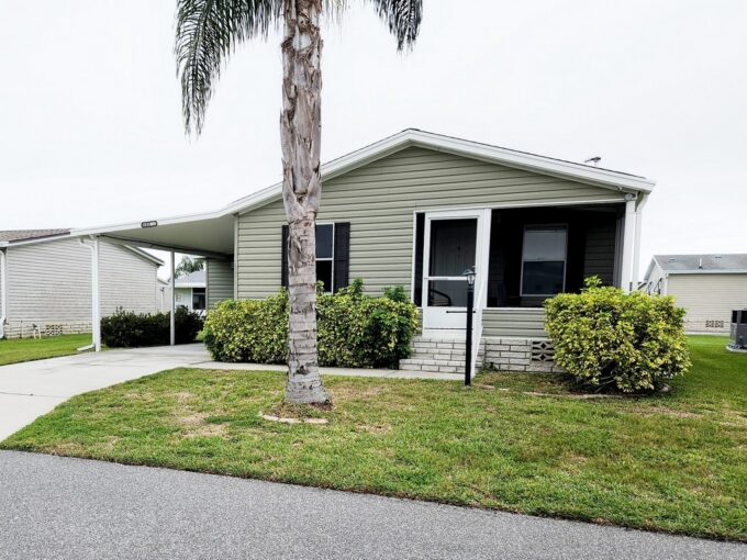 Charming Abode at 527 Leyland Cypress Way, Winter Haven, FL. Grey/Green Double-wide manufactured home with front-facing lanai, carport and driveway
