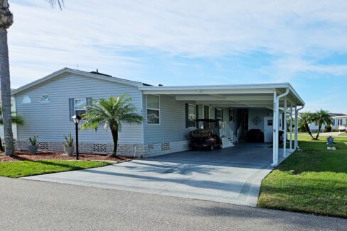 Easy to Love home at 235 Monterey Cypress BLVD, Winter Haven, IN. White Vinyl 2007 TIMB double-wide with deco driveway to wide carport covering entrance to home
