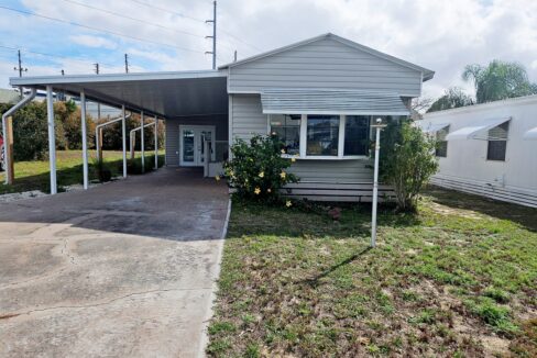 Motivated Seller is offering this remodeled, single-wide home with 1 bedroom and bath, gray siding, long driveway, wide covered carport, on corner lot of a cul-de-sac.