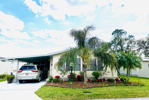 This great home at 1308 Deverly DR, Lakeland, FL, comes with an inspiring panoramic view from the back lanai and patio. Yellow vinyl sided double-wide manufactured home with tropical landscaping and wide driveway