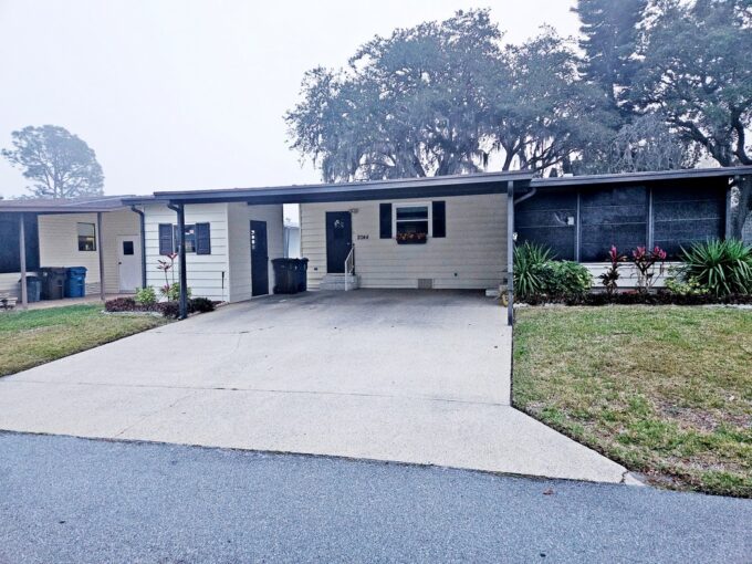 Your affordable retirement haven awaits you at 2044 Oriole LN, Lake Wales, FL. Yellow vinyl siding with brown trim. wide driveway from street to carport