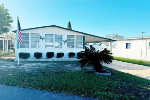 A blissful retirement haven at 24 Green Haven LN E, Dundee, Florida: White with black trim, doublewide manufactured home on leased lot.