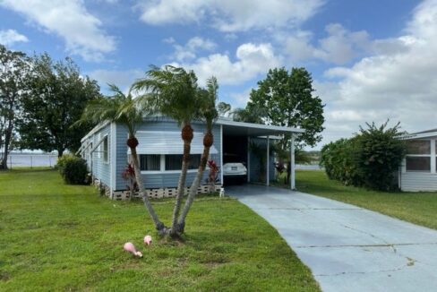 Your Waterfront Hideaway Awaits at 30 Hide A Way Lane, Winter Haven, Florida. Blue & White Single-wide home.