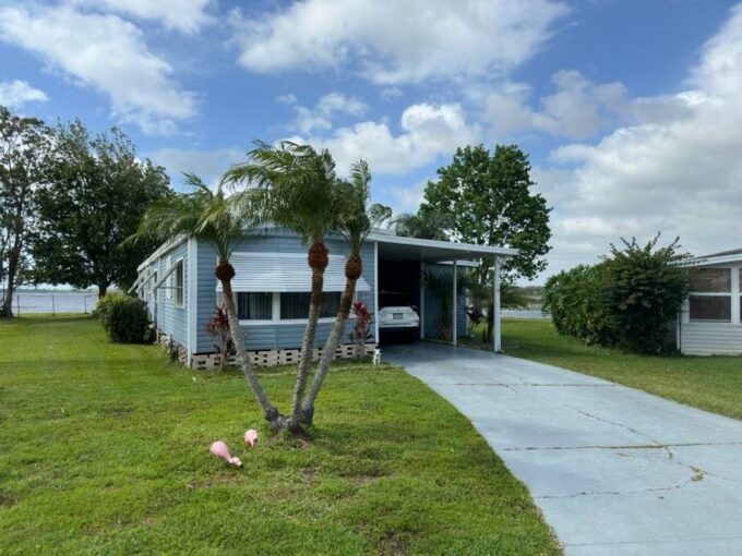 Your Waterfront Hideaway Awaits at 30 Hide A Way Lane, Winter Haven, Florida. Blue & White Single-wide home.