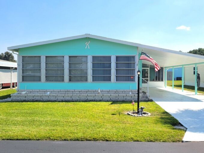 The Teal and white double-wide with large carport and deco driveway will offer an effortless move-in since it is fully furnished and ready.