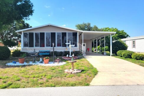 Great double-wide home with almond vinyl siding, a landscaped yard, long driveway and carport at 514 Caymen DR, in the spectacular community of Towerwood in Lake Wales, Florida
