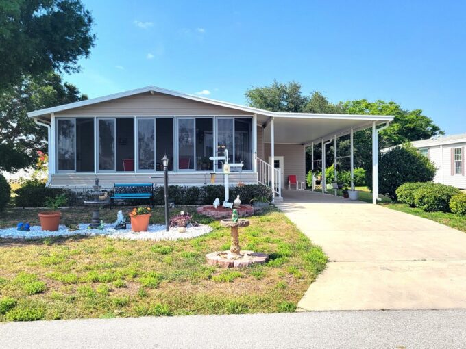 Great double-wide home with almond vinyl siding, a landscaped yard, long driveway and carport at 514 Caymen DR, in the spectacular community of Towerwood in Lake Wales, Florida