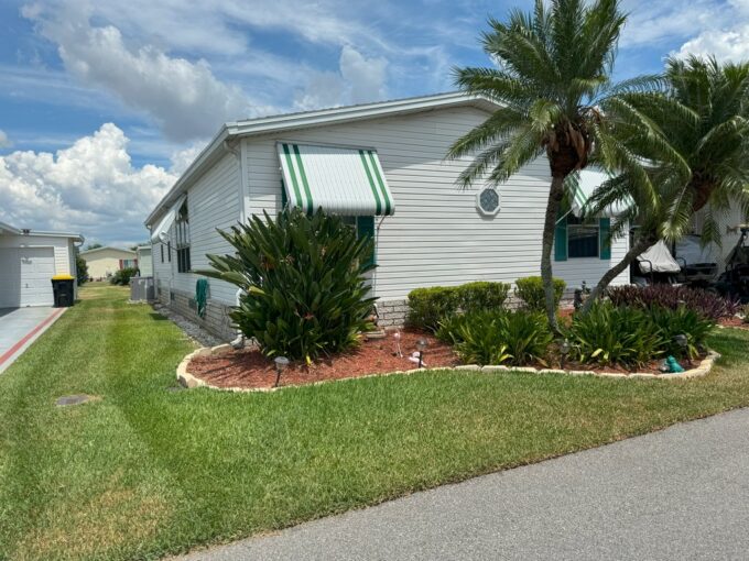 View 2 - Exterior view white siding with green accent color on awnings and side view of home with mature landscaping.