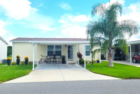 1202 Cypress Vine Lot #356 in Winter Haven. Beautiful 2021 model with nice landscaping, yellow vinyl siding, carport, gutters, private driveway.