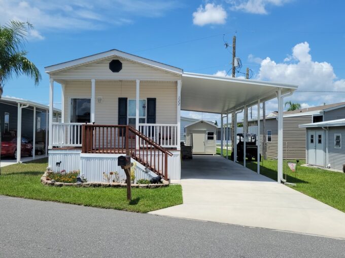 172 Valencia in Winter Haven community of Orange Manor East. Single wide 960 sq ft, yellow vinyl siding home with open front porch, carport, gutters, private driveway and curb side mail delivery.