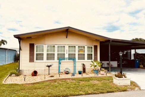 220 Gull Lane located at Tower Lakes in Lake Wales. Tan exterior color with brown accents, oversized private driveway, carport, screened porch, gutters.