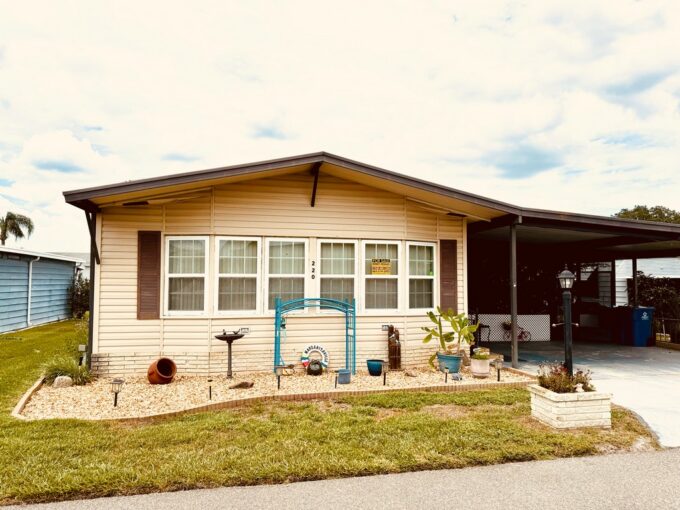 220 Gull Lane located at Tower Lakes in Lake Wales. Tan exterior color with brown accents, oversized private driveway, carport, screened porch, gutters.