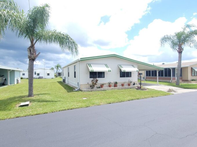 View 2 - Private driveway, curb side mail delivery, carport, gutters, lanai 12 x 13, shed 10 x 8. Cream with green accents.