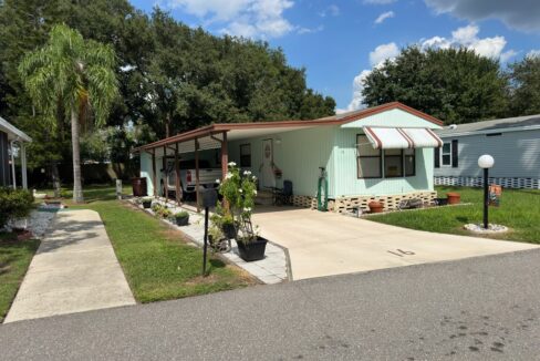 Single wide home has 2 bedroom and 2 bathrooms, it is mint green color on vinyl siding with brown accents, brick skirting, carport, private driveway, awnings, gutters, shed and lanai.