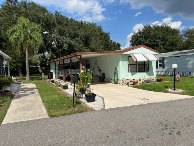 Single wide home has 2 bedroom and 2 bathrooms, it is mint green color on vinyl siding with brown accents, brick skirting, carport, private driveway, awnings, gutters, shed and lanai.