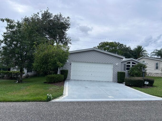 Triple wide with two car garage in Lady Lake's community of Water Oak Country Club Estates. Gray vinyl siding with 3 bedroom and 2 bathroom.