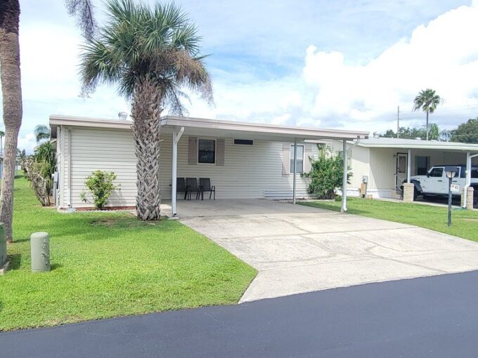 Private driveway, carport, storage shed, gutters, pale yellow vinyl siding.