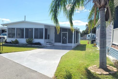 White aluminum siding, private driveway, screened lanai to the right side of home, glass lanai in the front of the home. Storage shed is through the screened lanai. Curb side mail delivery is offered at this community.