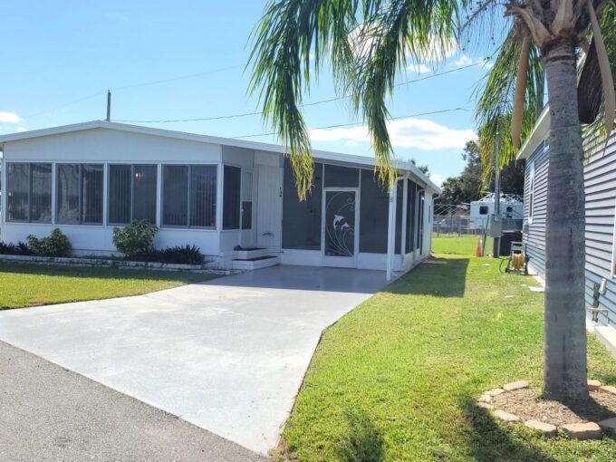 White aluminum siding, private driveway, screened lanai to the right side of home, glass lanai in the front of the home. Storage shed is through the screened lanai. Curb side mail delivery is offered at this community.