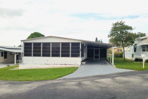 104 Baywood Dr in Dundee Florida located in Dell Lake Village community. Double wide home with white vinyl siding, awnings, carport, gutters, screened lanai, storage shed, private driveway, curb side mail delivery.