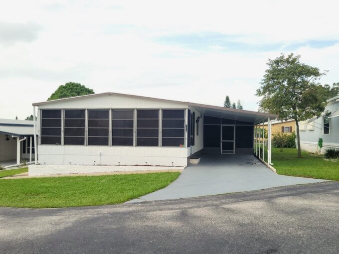 104 Baywood Dr in Dundee Florida located in Dell Lake Village community. Double wide home with white vinyl siding, awnings, carport, gutters, screened lanai, storage shed, private driveway, curb side mail delivery.