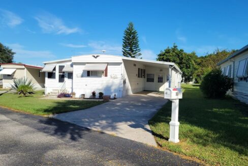 White siding with awnings, carport, private driveway, curb side mail delivery, gutters, two lanais, storage shed, this home is turnkey.