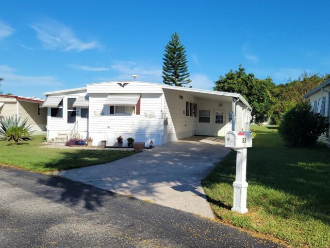 White siding with awnings, carport, private driveway, curb side mail delivery, gutters, two lanais, storage shed, this home is turnkey.