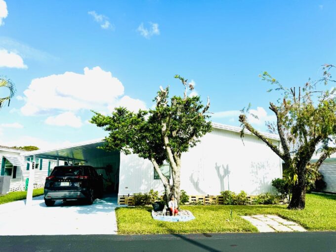 White vinyl siding with carport, gutters, private driveway, storage shed and large lanai.