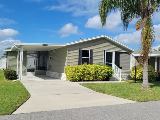 Charming home with green vinyl siding , black shutters, private driveway, carport, storage shed and 2 screened lanais, manicured yard.