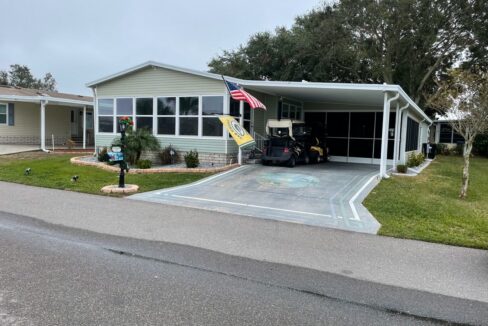 The extensive, 16x31 screened carport features dual outdoor ceiling fans, a flat-screen TV, and generous seating. This is a perfect place to enjoy the beautiful Florida weather with your friends and family. Adjacent is an oversized utility shed complete with a sink, extra refrigerator, and workshop space—perfect for post-golf cleanup or DIY projects.