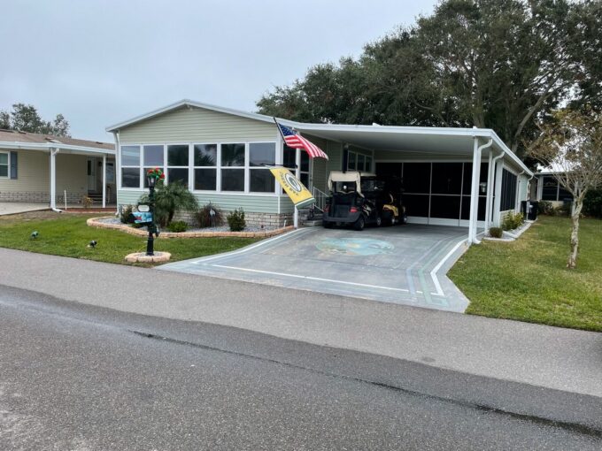 The extensive, 16x31 screened carport features dual outdoor ceiling fans, a flat-screen TV, and generous seating. This is a perfect place to enjoy the beautiful Florida weather with your friends and family. Adjacent is an oversized utility shed complete with a sink, extra refrigerator, and workshop space—perfect for post-golf cleanup or DIY projects.