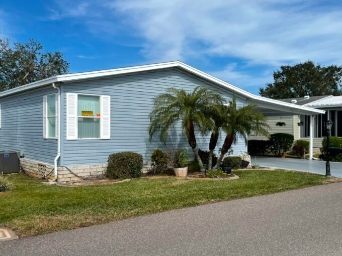 Private driveway, carport, nice landscaping, blue siding with white shutters.