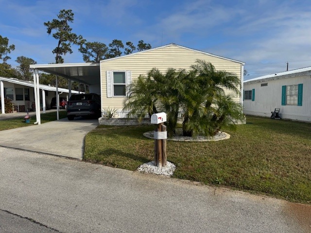 Yellow double wide with curb side mail delivery, private driveway, carport, gutters, storage shed, mature landscaping.