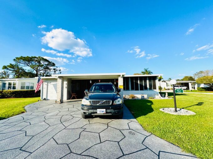 Corner lot, deco driveway, golf cart garage, lanai in front of home, mostly furnished home in golf course 55+ community in Lakeland, Florida.