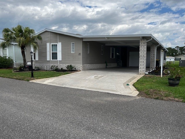Vinyl siding, carport, private driveway, golf cart garage, golf cart included plus lanai on a golf course.