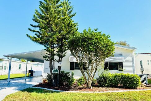 Mature trees, deco driveway, carport, access ramp under carport, golf cart garage with golf cart. Awnings over windows. Large lot with privacy.