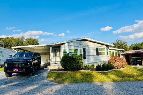 Vinyl siding is gray with black trim, deco driveway, carport, gutters, 4 season room, golf cart garage. Two bedrooms with 2 bathrooms.